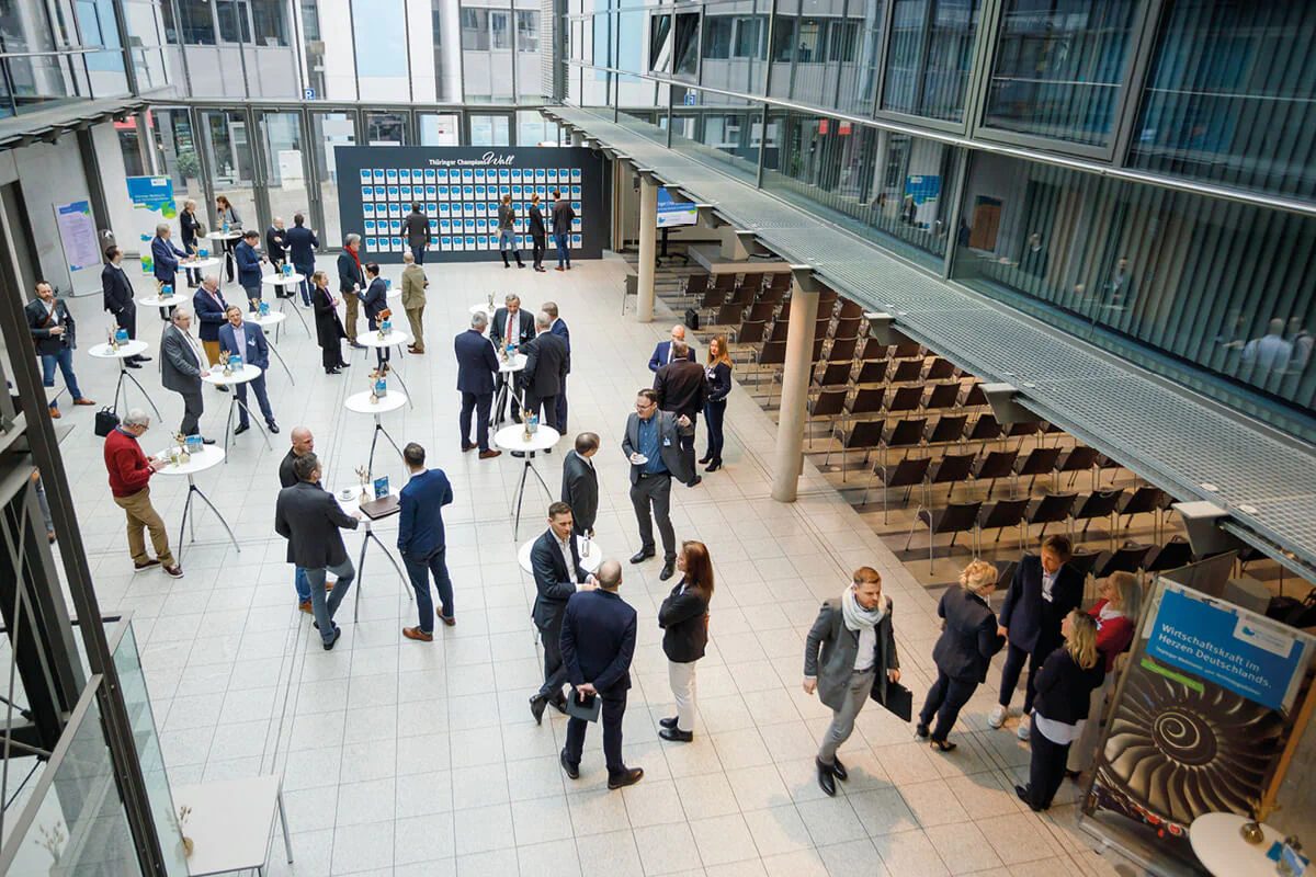 Glasüberdachtes Atrium im COMCENTER Brühl mit Gästen an Stehtischen