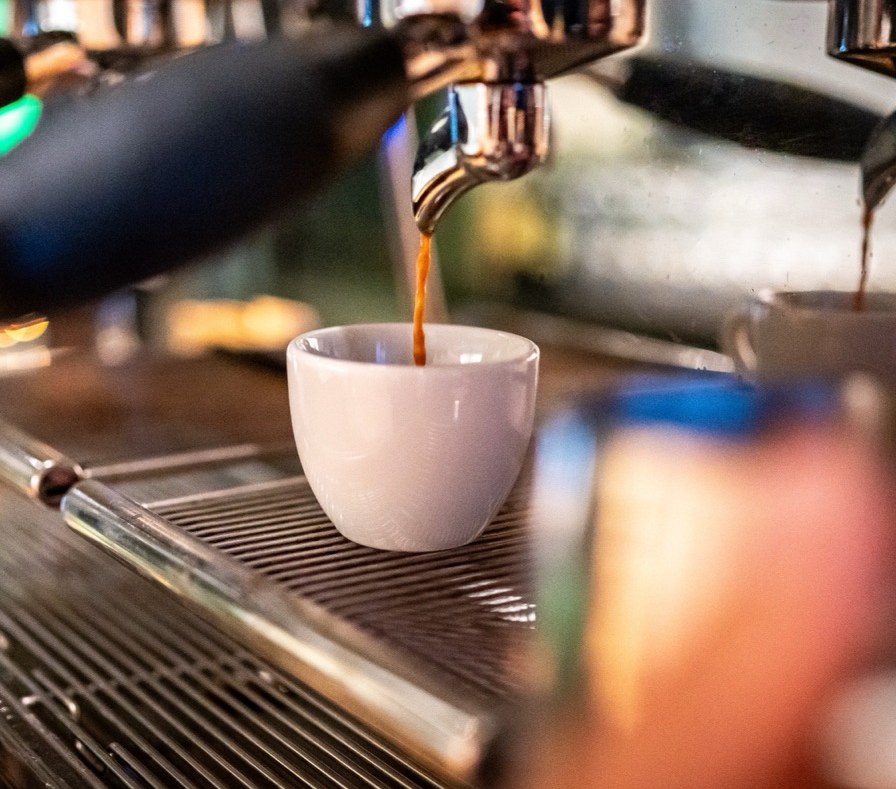 Espresso läuft in eine weiße Tasse, naher Ausschnitt