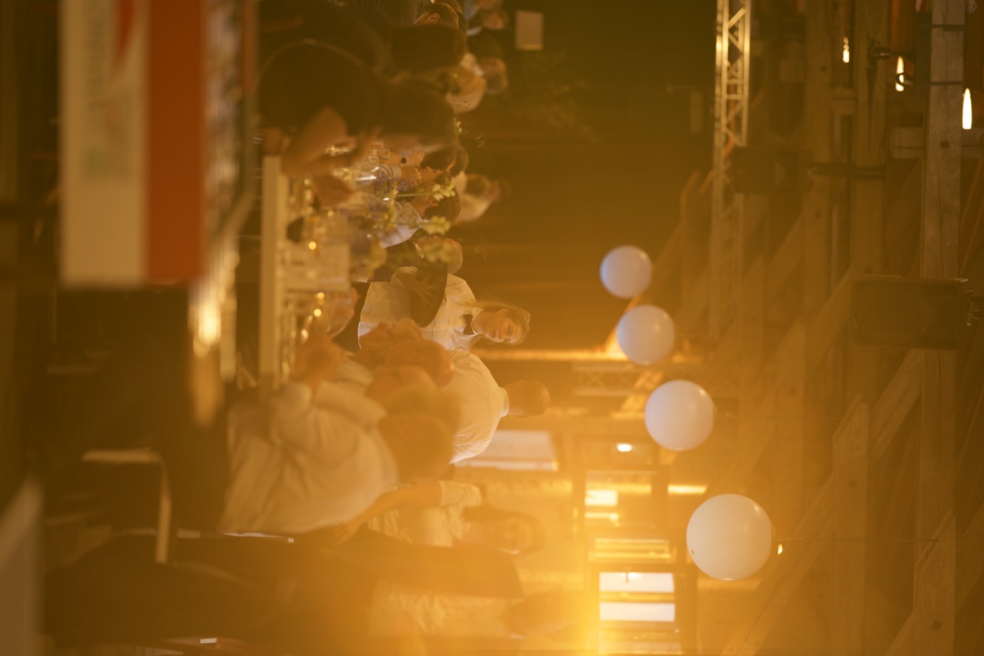 Voll besetzte lange Tafeln im goldenen Abendlicht der Halle 6