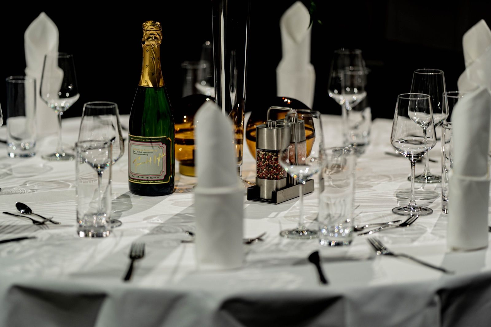 Tischdetail mit Sektflasche, Gläsern und stehenden Servietten auf weißer Tafel