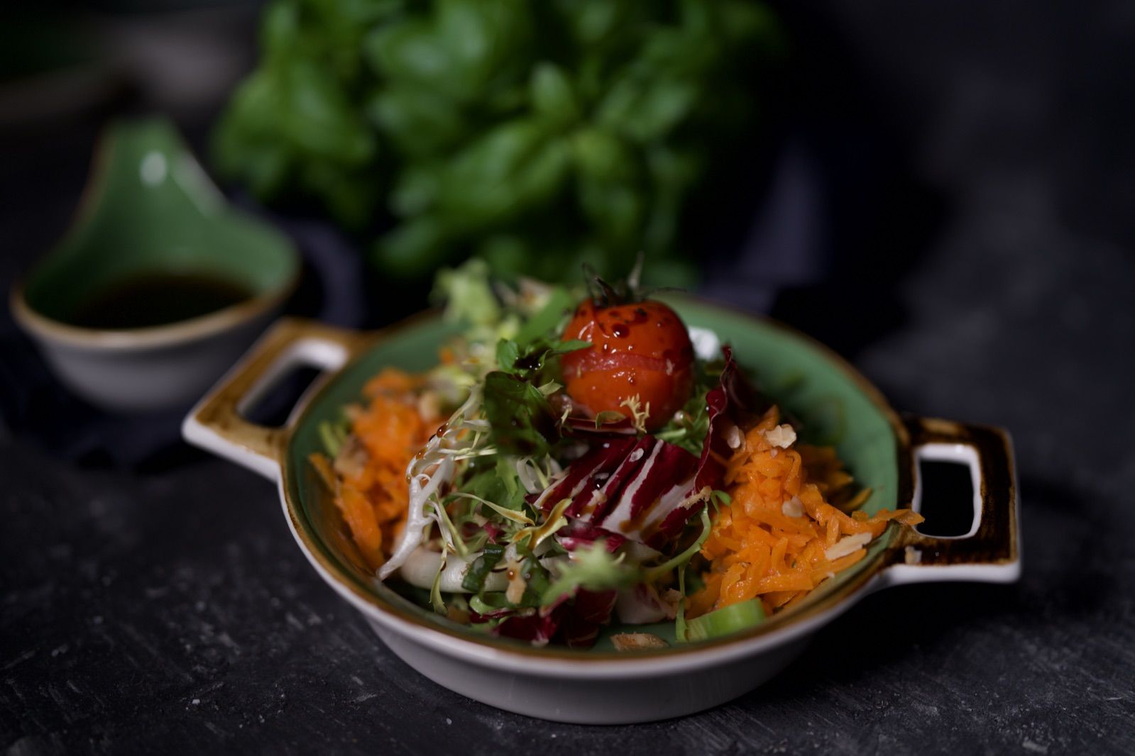 Bunter Salat mit Karotten, Radicchio und Tomate in einer grünen Gusspfanne