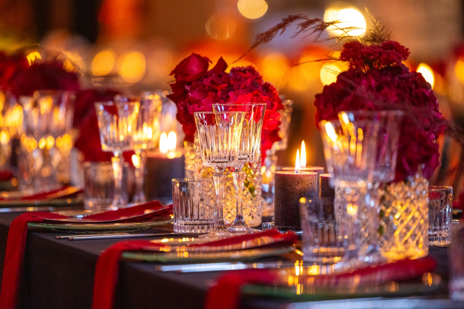 Festliche Tafel mit Kerzen, Gläsern und roten Blumen in der Halle 6