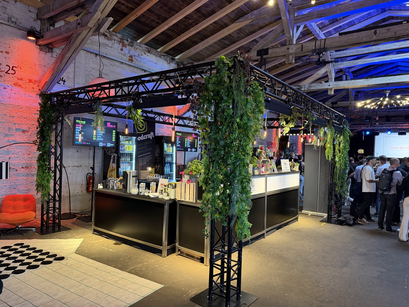 Bar-Modul aus schwarzem Trussing mit Begrünung, Menü-Screens und Lichttechnik im Einsatz
