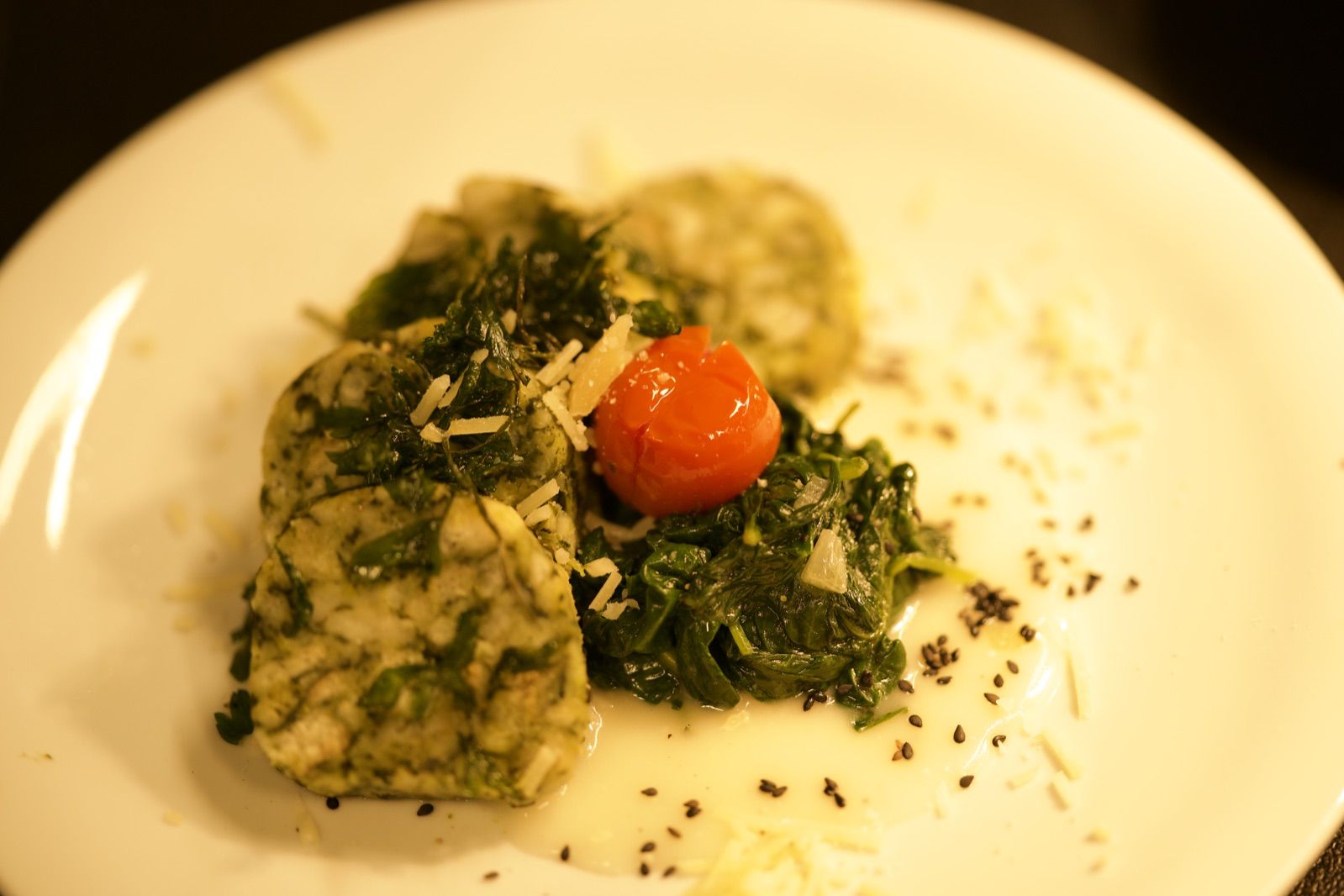 Vegetarischer Teller mit grüner Terrine, Blattspinat und Kirschtomate