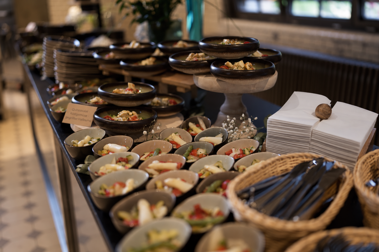 Kleine Salatschalen, Besteckkörbe und Servietten auf einem Buffet