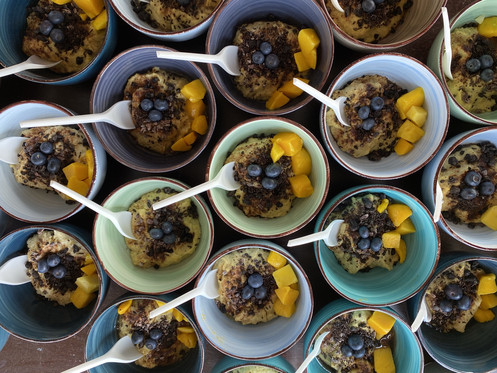 Schalen mit Müsli, Mangostücken und Blaubeeren, von oben fotografiert