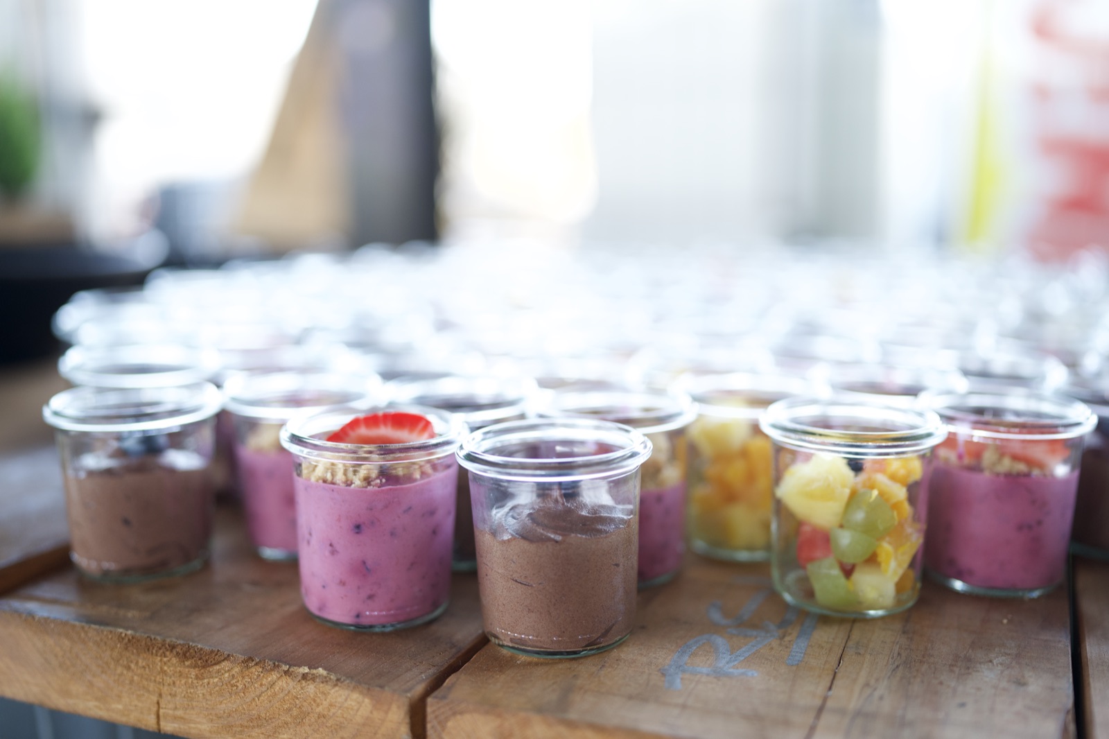 Reihen von Dessertgläsern am Buffet, Salatschüsseln im Hintergrund