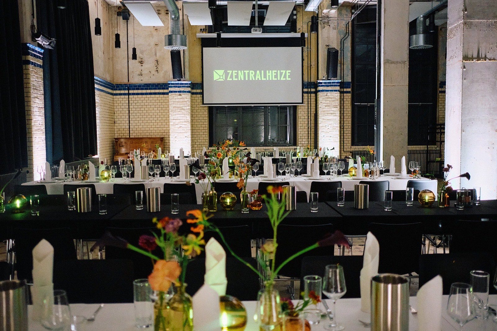 Festlich gedeckte Bankett-Tafeln mit Blumen und Kerzen in der Maschinenhalle der Zentralheize